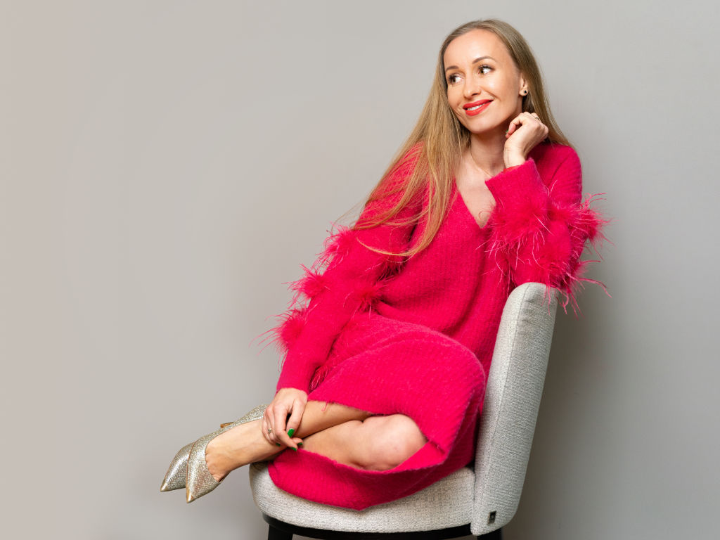Stilberaterin Kashia Lehmann in einem pinken Strickkleid sitzend und lächelnd